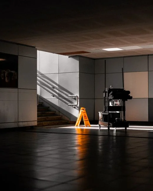 Minimalist room with a person cleaning a chair using a sponge and cleaning product.